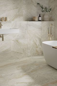 a bath tub sitting next to a white sink in a bathroom with marble walls and floors