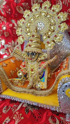 an idol is sitting on top of a red cloth covered tablecloth with gold and silver decorations