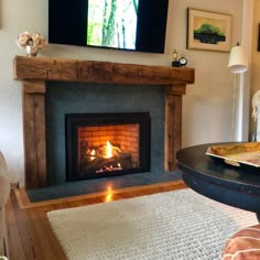 a living room with a fire place and television on the wall above it's fireplace