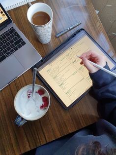 a person sitting at a table writing on a clipboard next to a laptop computer