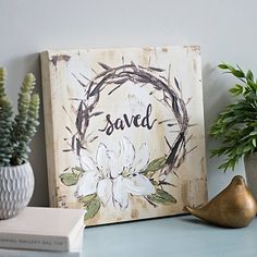 a wooden sign sitting on top of a table next to a potted plant and books