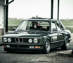 an old bmw is parked on the side of the road in front of a building