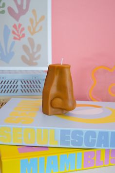 a candle is sitting on top of two books in front of a pink and yellow wall