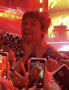 a group of people holding up cell phones in front of each other at a concert