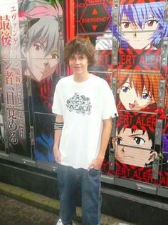 a young man standing in front of some anime characters on the side of a building