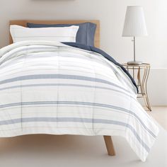 a white bed with blue and gray striped comforter