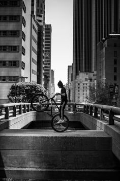 black and white photograph of a man on a bicycle in the middle of a city