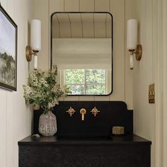 a bathroom sink with a mirror above it and flowers in a vase on the counter