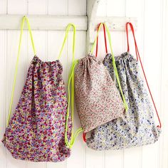 two drawstring bags hanging on the wall next to each other with hooks in them