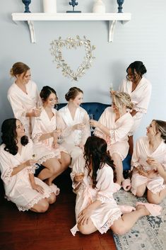 a group of women sitting on top of a blue couch in pink robes and holding champagne glasses