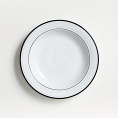 an empty white plate with blue trim on the rim is sitting on a white surface