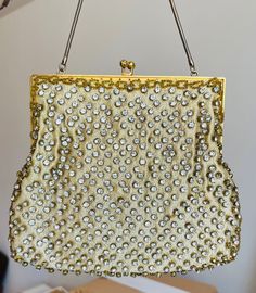 This is a gorgeous vintage gold tone evening bag/purse.  The frame is gold, the gold silk is embellished with  rhinestones and gold seed beads on the edges.  The inside is beige satin in great condition.  There are two rhinestones missing on the plead on the side - hardly visible.  The chain is in excellent condition as well as the clasp.   A beautiful bag for a special occasion.  Measurements Height- 6 3/4 Width - 8" Drop - 6 1/2" My store strives for excellence, honesty and transparency.  Please ask questions and/or request additional photos, if needed, before making a purchase.     Please note: *Every item in my store is vintage used, unless stated in the description otherwise.     *My store does not accept returns.   *My store does not issue refunds, unless an item has not been describ Gold Silk, Evening Purse, Beautiful Bags, Gold Beads, Vintage Gold, Evening Bags, Seed Beads, Special Occasion, Gold Tones