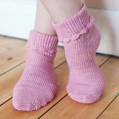 a close up of a person's legs wearing pink knitted socks with ruffles