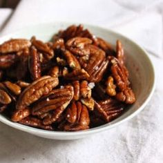 a white bowl filled with pecans on top of a table