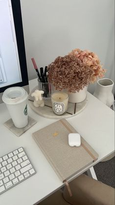 a desk with a computer, keyboard and flowers on it