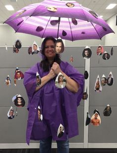 a woman standing in front of a wall with pictures on it and an umbrella over her head