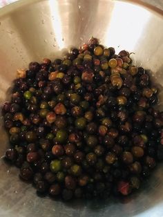 a metal bowl filled with olives on top of a counter