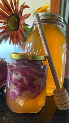 two jars filled with food sitting on top of a table next to a wooden spoon