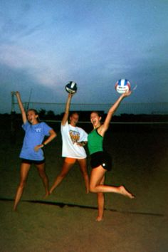 three girls jumping in the air to catch a volleyball