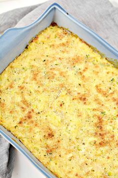 a casserole dish with cheese and herbs in it on a gray napkin next to a fork