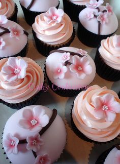 there are many cupcakes with pink frosting and flowers on the top one