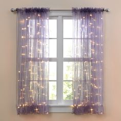 a window with purple curtains and lights on the curtain is shown in front of a white wall