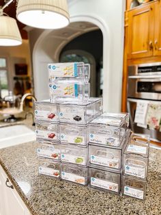 a stack of clear plastic containers sitting on top of a counter next to a sink