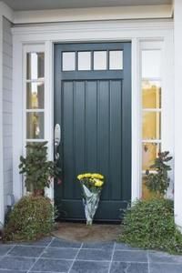 a blue front door with yellow flowers in the potted planter next to it