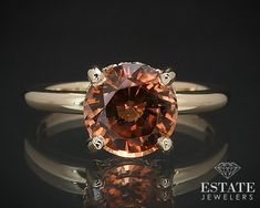 an orange diamond sits on top of a white gold engagement ring with diamonds around it