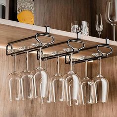 several wine glasses hanging from a shelf in a kitchen