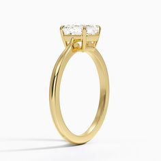 a yellow gold engagement ring with an oval cut diamond in the center, on a white background