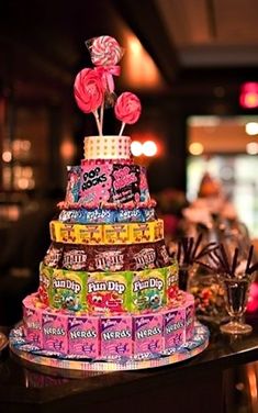 a multi - tiered cake decorated with candies and lollipops sits on a table