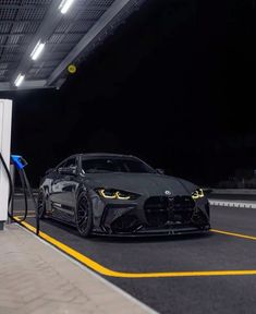 a black sports car at a gas pump in the middle of an empty parking lot