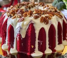 a red velvet bundt cake with pecans and icing drizzled on top