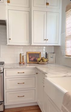 a kitchen with white cabinets and gold trim on the counter tops, along with a silver dishwasher