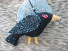 a small black bird sitting on top of a wooden table next to a gray rock