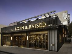 a store front with the words born and raised lit up