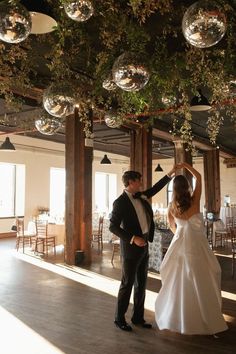 the bride and groom are dancing together in their wedding reception room with disco balls hanging from the ceiling