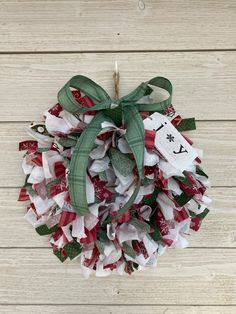 a christmas wreath hanging on the side of a wooden wall with a tag attached to it