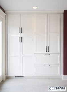 an empty kitchen with white cabinets and purple walls