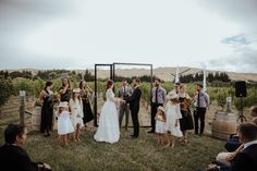 a group of people standing around each other in front of some barrels and wine glasses