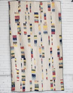 a quilt hanging up against a white brick wall