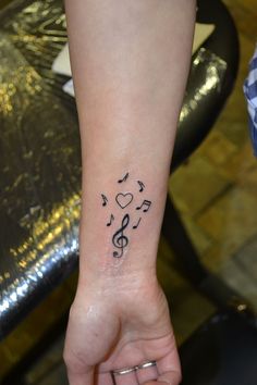 a woman's wrist with musical notes and hearts tattooed on her left side arm