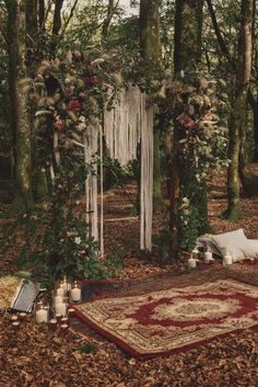 an outdoor wedding ceremony in the woods with candles and rugs laid out on the ground