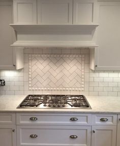 a stove top oven sitting inside of a kitchen next to white cupboards and drawers