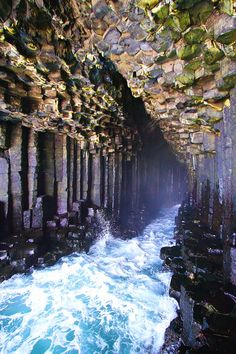 the inside of a cave with water coming out of it and rocks on either side