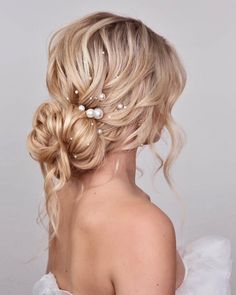 a woman with blonde hair and pearls in her hair is wearing a white dress, looking back