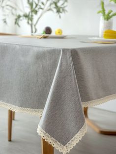 a table with a white doily on it and flowers in vases behind the table