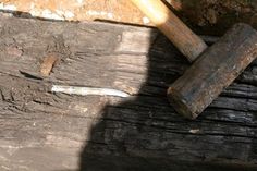 an old hammer is laying on top of a piece of wood