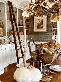 a wooden table topped with white pumpkins next to a shelf filled with plates and bowls